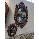 A Rococo style oval plaster wall mirror, with a floral surround, 58cm wide, 93cm high, and a further