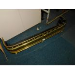 A Georgian brass and iron fender, with pierced bands, decorated with brass beads, raised on turned