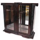 A 19thC Brazilian mahogany glazed display cabinet, heavily carved with curved glazed doors,