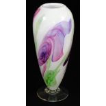 A 20thC studio Our Glass vase, predominantly in purple and green, on a cream ground, on a plain