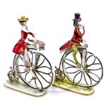 A pair of Capodimonte style penny farthing figures, each polychrome decorated predominantly in pink,