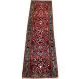 A Hammadan carpet runner, with stylised floral central field on red ground, enclosed by triple