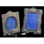 An Edwardian silver photograph frame, of shaped rectangular form, heavily repousse decorated with