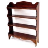 An Edwardian stained pine bookcase, of rectangular form with shaped sides and plain shelves, on