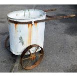 An early 20thC mobile bran tub, with oval articulated centre on a wrought iron stand with two spoked