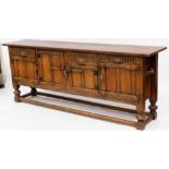 A heavily carved 20thC oak sideboard, of rectangular form with four shaped doors on heavy compressed