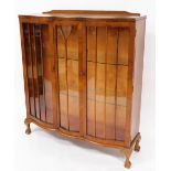 A mid 20thC serpentine display cabinet, the glazed front set with vertical bars with removable