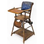 An early 20thC child's elm chair, with tray front and foot rest on wheeled back with a galleried