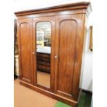 A Victorian mahogany triple door wardrobe, with moulded cornice, raised above a central mirror