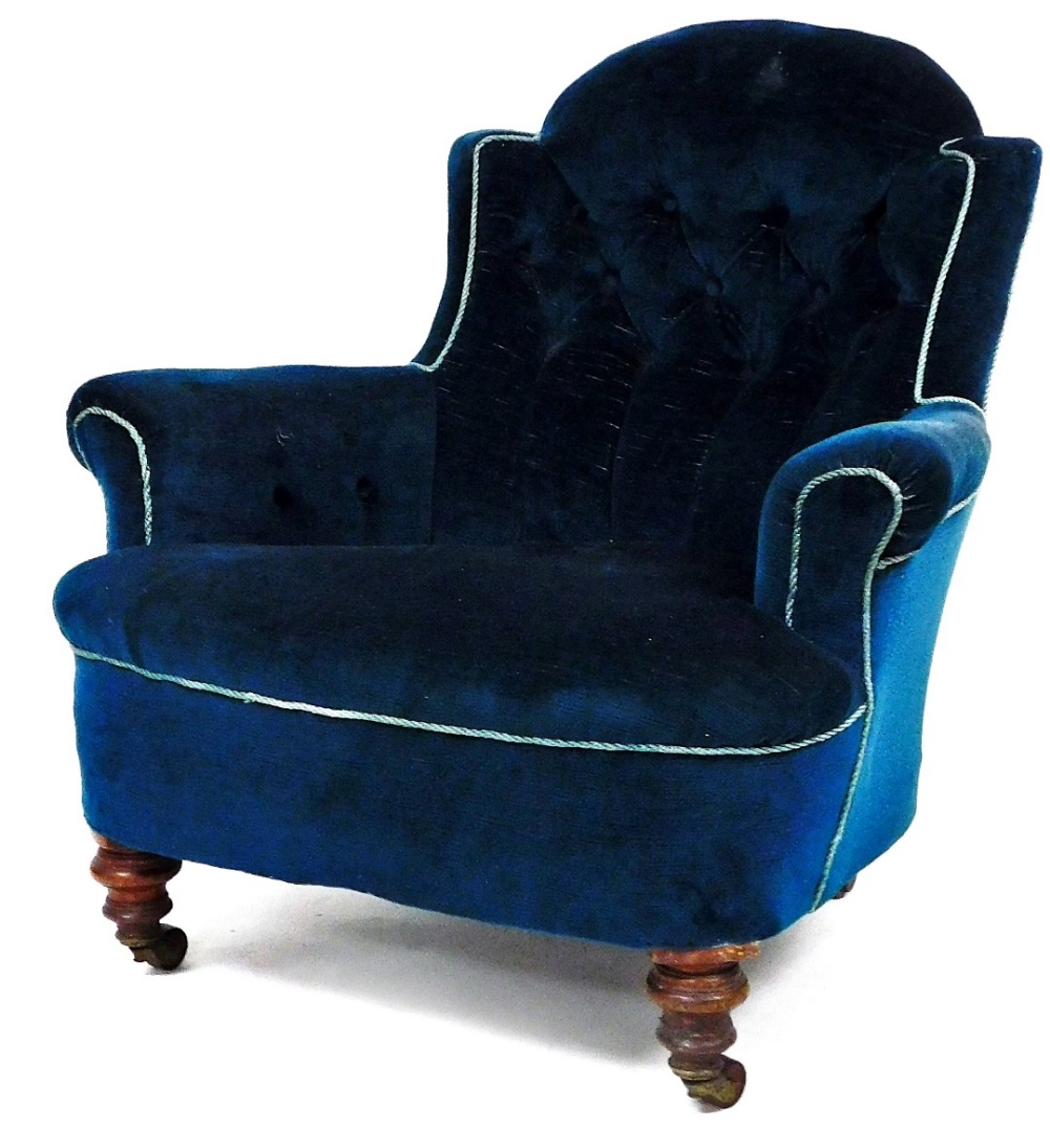 A Victorian low armchair, with buttoned velvet upholstery and turned fore legs.