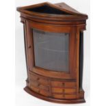 A 20thC mahogany hanging curved corner cupboard, with glazed door raised above six spice drawers