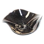 A 20thC studio Our Glass dish, of clover leaf form, in black and white speckled decoration, on