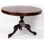 A Victorian mahogany tilt top table, the circular top with moulded outline on a heavily carved