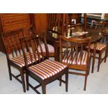 A Stag Minstrel extending circular dining table and eight chairs, each in Regency stripe style