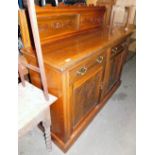 An Edwardian walnut sideboard, with carved back raised above two frieze drawers and double