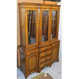 A 20thC oak break front display cabinet, with three upper glass sections raised above a section of