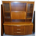 A teak display cabinet, with central opening flanked by glazed doors above three drawers and