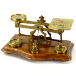 A set of late Victorian walnut and brass postal scales with weights, 18cm wide.