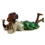 A cold painted bronze figure of an Arab boy smoking a cigarette whilst lying on the floor, picked ou