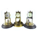 Three brass Anniversary type clocks, each with enamel type dials and Roman numerals, two with domes