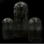Three glass clock domes, the largest 37cm high, the other two approx 19cm high.