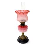 A Victorian cast brass oil lamp, with two tone pink reservoir, and a cranberry tinted etched shade d