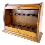 An Edwardian oak pipe rack, with a domed tambour door, enclosing fitted interior, with recess on a p