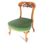 A Victorian walnut nursing chair, with a shaped and pierced back, a green velvet padded seat on shor
