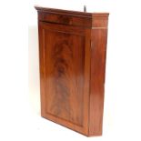 An early 19thC mahogany hanging corner cabinet, with a single flame mahogany figured door, 105cm hig