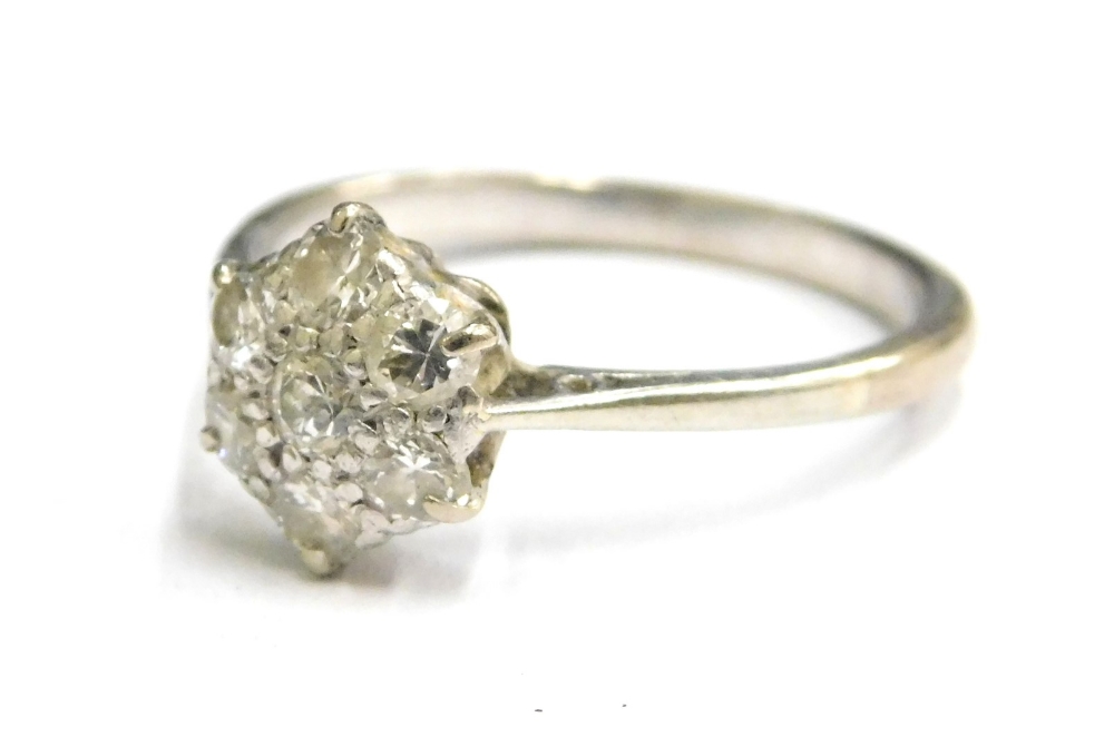 A diamond cluster ring, with central flower design ring head in claw setting, with pierced scroll de