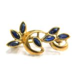 A 9ct gold floral bar brooch, of two twist design set with seven blue sapphires, 2.5cm wide, 1.8g al