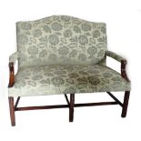 A mahogany sofa in George III style, with a shaped back upholstered in pale blue damask fabric, on c