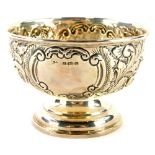 An Edwardian silver sugar bowl, embossed with scrolls, flower heads, etc., surrounding two vacant ca