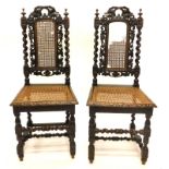 A pair of late 19thC oak side chairs, each carved with grapes, vines and spiral twists, with a caned