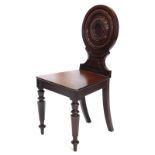 An early 19thC mahogany hall chair, the back decorated with a moulded roundel, with a solid seat on