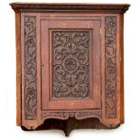 A late 19th-early 20thC mahogany hanging corner cabinet, carved overall with scrolls, flowers, etc.,