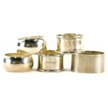 A collection of silver napkin rings, to include a pair of circular shaped pieces, and an oval napkin