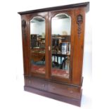 An Edwardian mahogany wardrobe, with a later moulded cornice above two arched mirrored doors, flanke