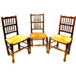 A set of three Lancashire ash spindle back dining chairs, each with a rush seat on turned tapering l