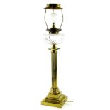 An early 20thC brass oil lamp, with cut glass reservoir on a reeded stem, terminating in a stepped s