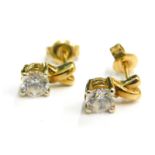 A pair of modern earring studs, each with cross design top and single CZ set stone, yellow metal, un