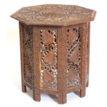 An Indian carved occasional table, the octagonal top decorated with flowers, leaves, etc., on a simi