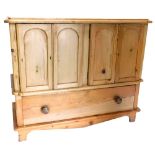 A pine side cabinet, the top with a moulded edge above two pairs of doors, each with arched panels e