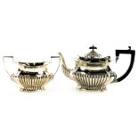 An Edwardian rectangular silver teapot, with rounded corners and part fluted decoration, on an eboni