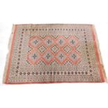 A machine woven Persian style rug, with a design of pale blue lozenges on a pink ground, 173cm x 127