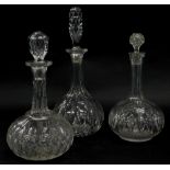 Three similar bottle shaped decanters and stoppers, each with cut decoration.