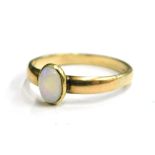 An opal set dress ring, with single oval opal in rub over setting, on a plain band, yellow metal, ma