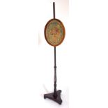 A 19thC mahogany pole screen, the oval banner with an embroidered woolwork panel of flowers within a