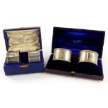 Two pairs of silver napkin rings, one with engraved decoration and vacant cartouches, the other comp