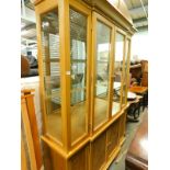 A lightwood breakfront display cabinet.